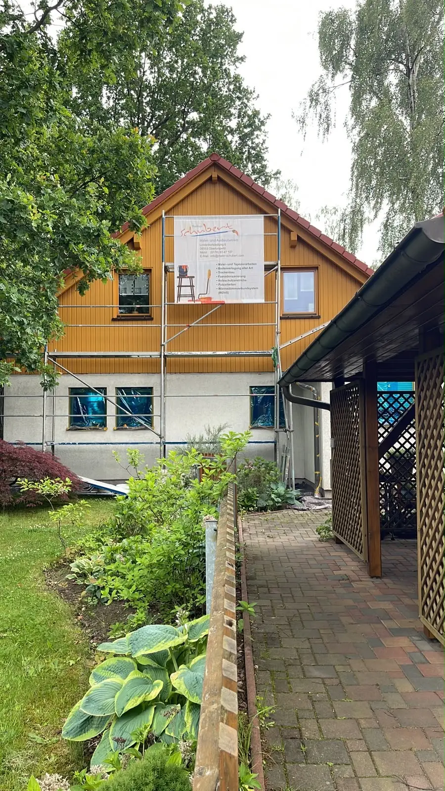 Frisch gestrichenes Haus mit gelber Holzfassade und Gerüst